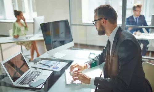 Ein männlicher Mitarbeiter, der auf der Tastatur tippt und auf den Computerbildschirm schaut